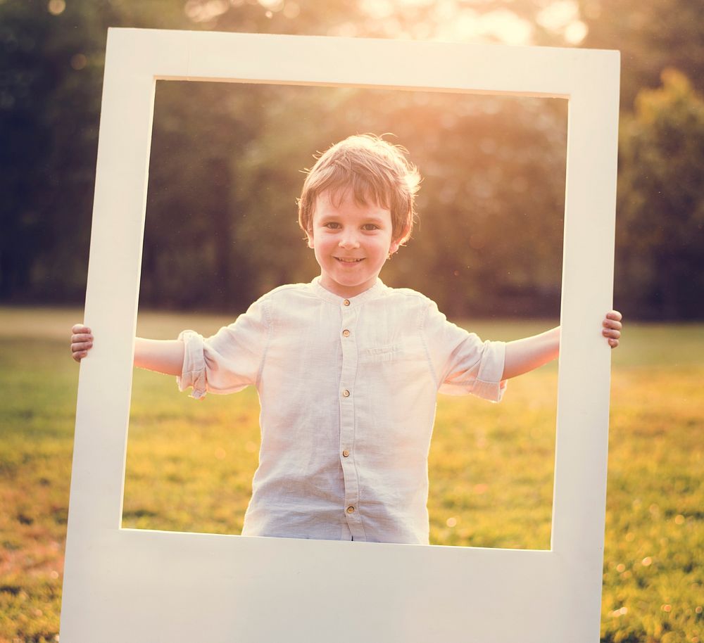 A boy is holding a frame in a park