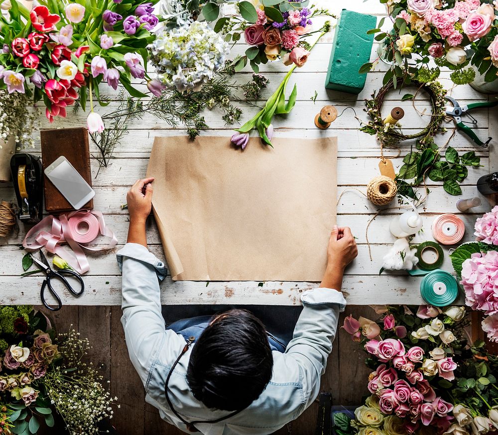 Florist Showing Empty Design Space Paper on Wooden Table with Fresh Flowers Decorate