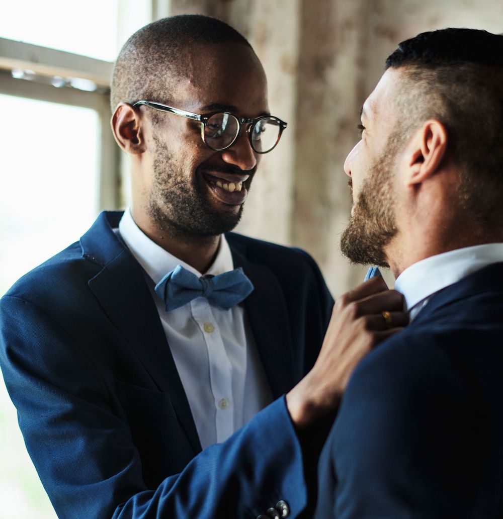Closeup of gay couple helping each other dress up