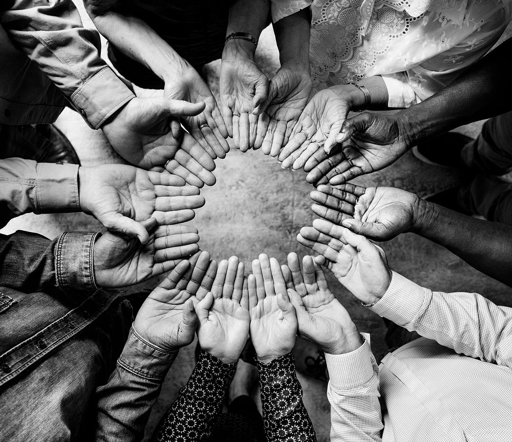 Group of diverse hands palms circle support together teamwork aerial view grayscale