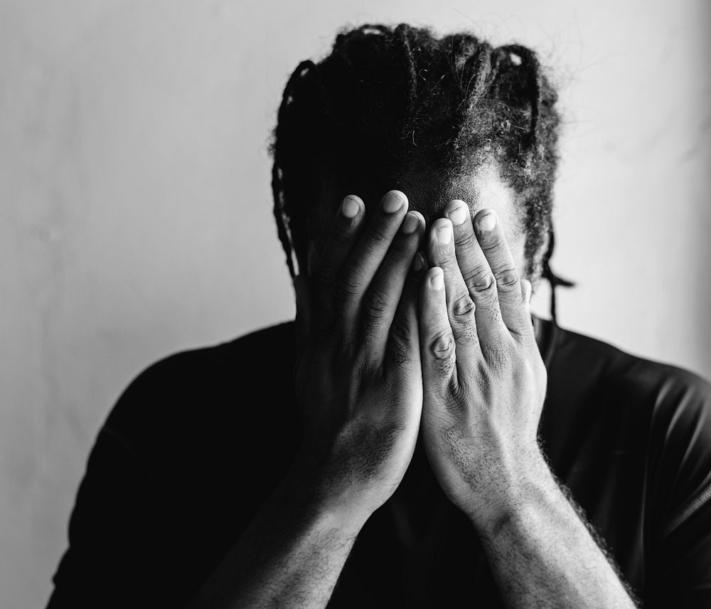 African American man covering his face with his hands 