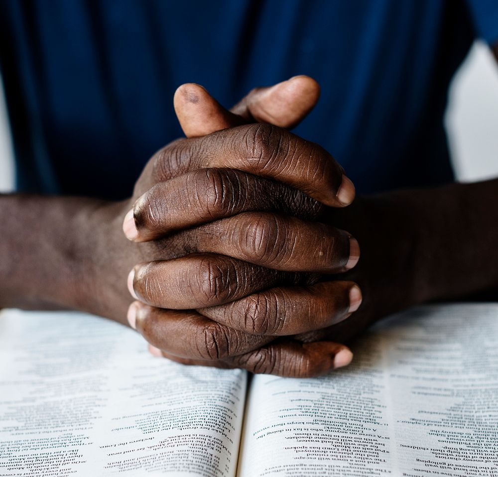 African American male hands resting on an open bible 