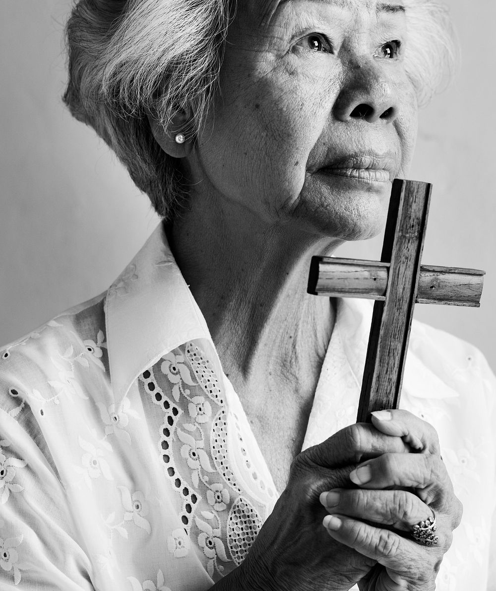 Elderly Asian woman holding a cross 