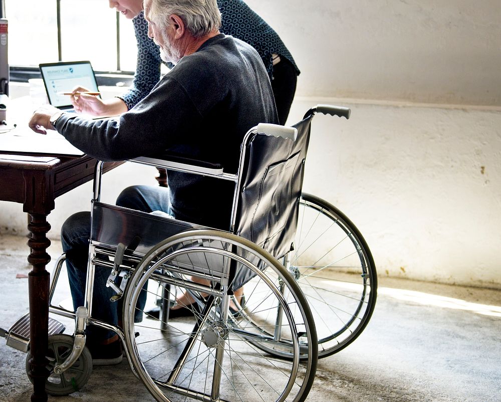Side view of elderly man sitting on wheelchair looking at life insurance contract form