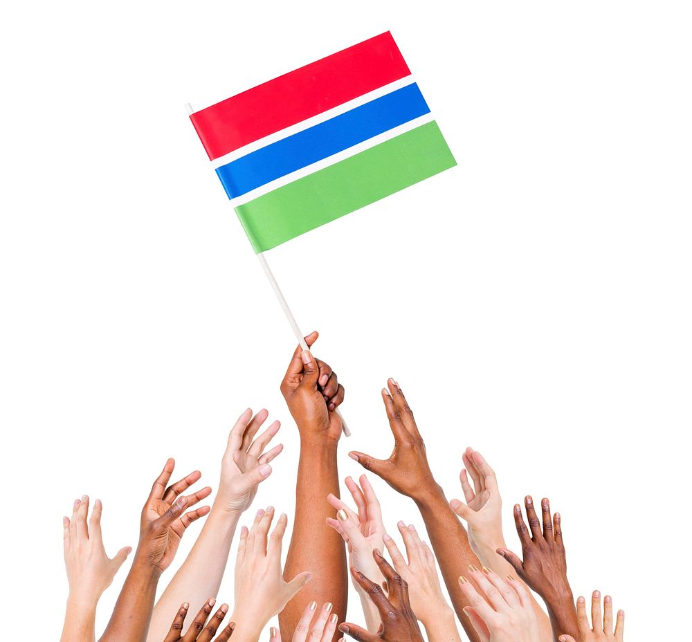 Group of multi-ethnic people reaching for and holding the flag of Gambia.