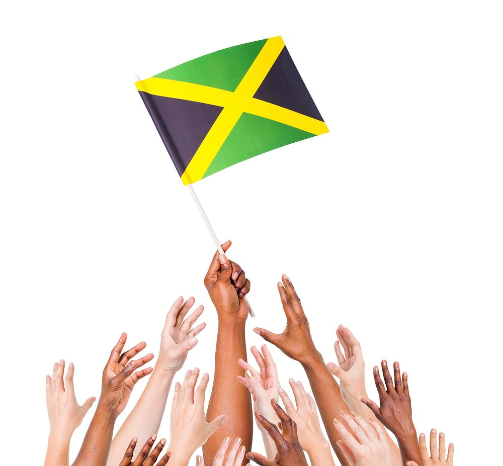Group of multi-ethnic people reaching for and holding the flag of Jamaica.