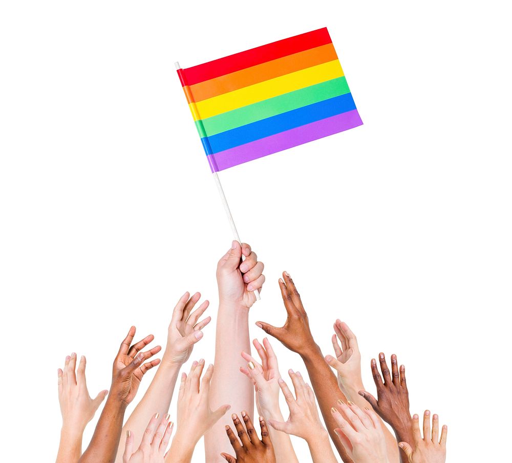 Human hand holding LGBT Flag among multi-ethnic group of people's hand