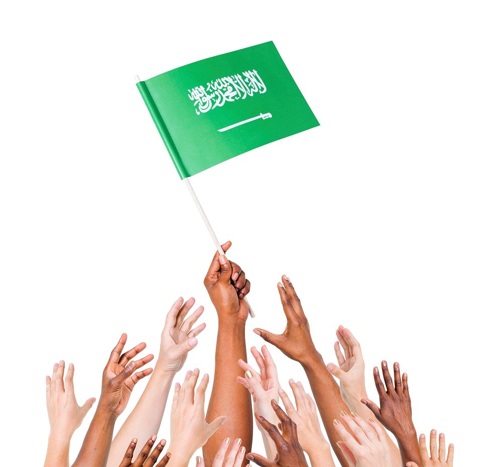 Group of multi-ethnic people reaching for and holding the flag of Saudi Arabia.