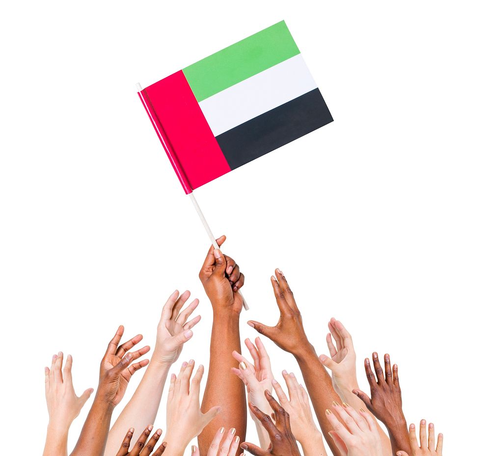 Human hand holding United Arab Emirates flag among multi-ethnic group of people's hand