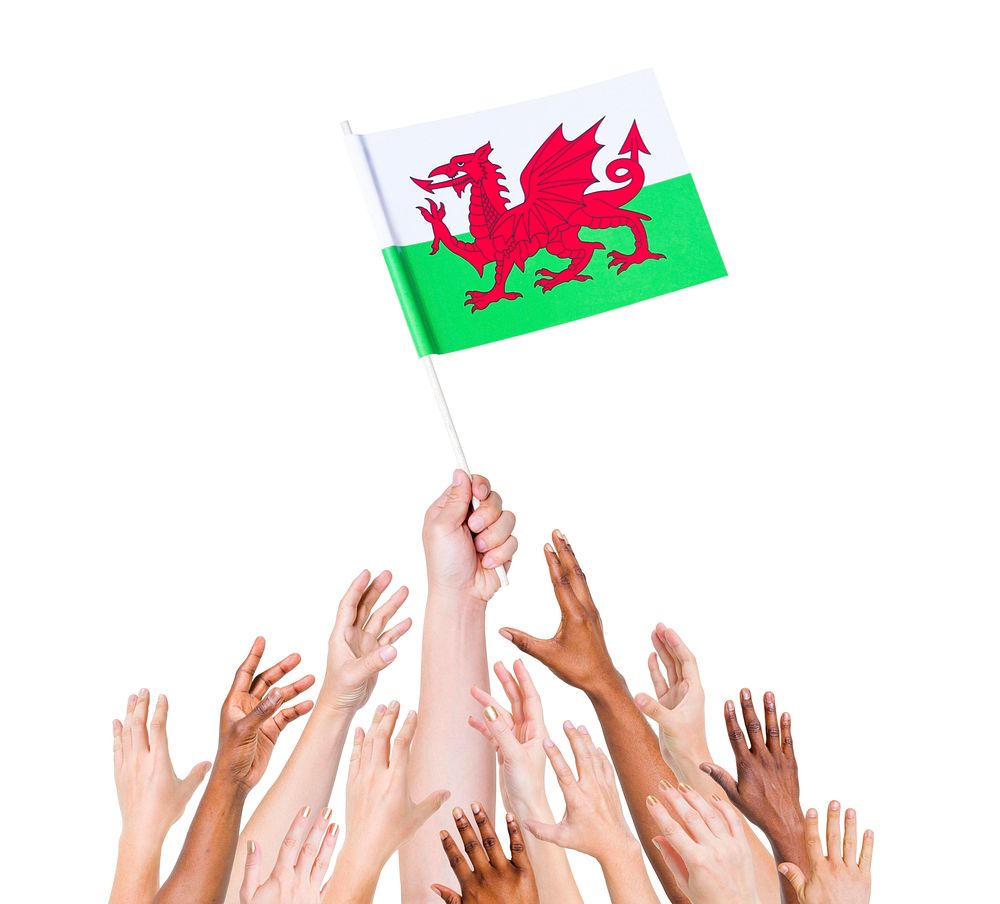 Human hand holding Wales flag among multi-ethnic group of people's hand