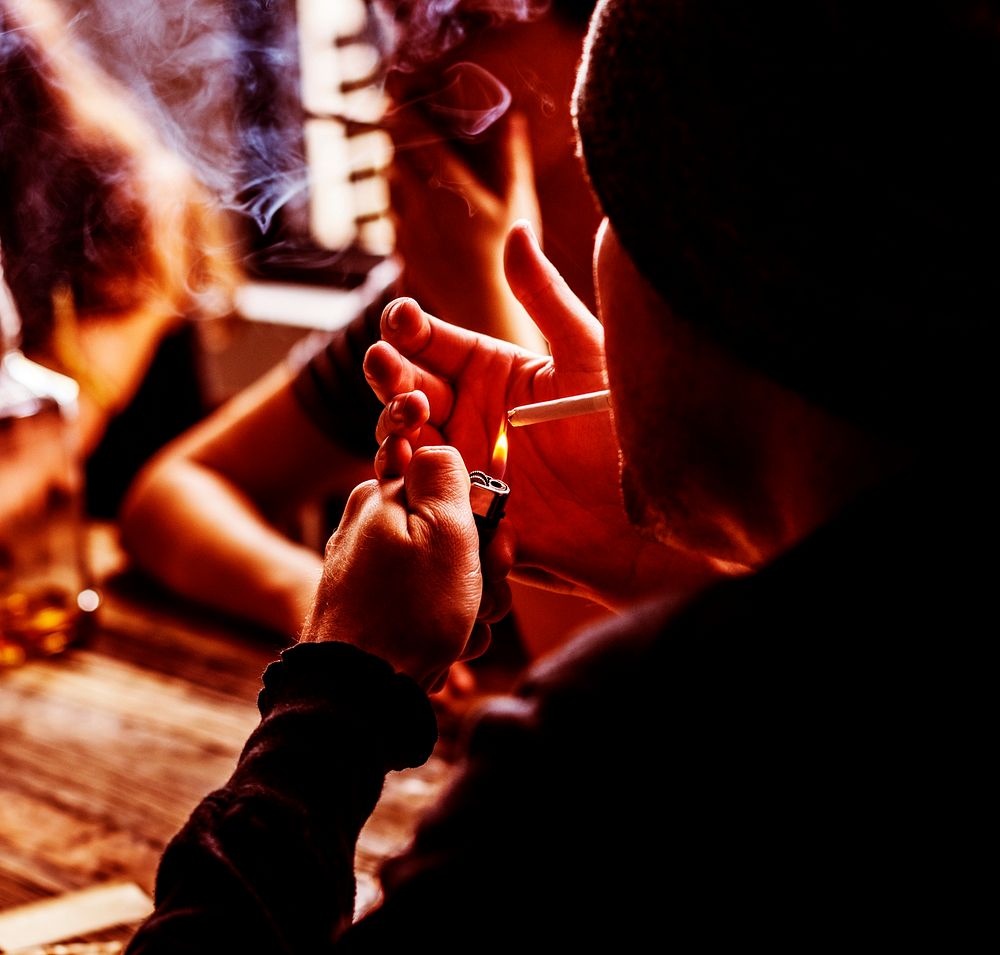 Man lighting a cigarette with his friends
