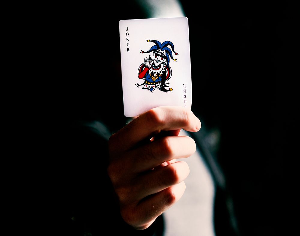 Male card dealer holding a joker card