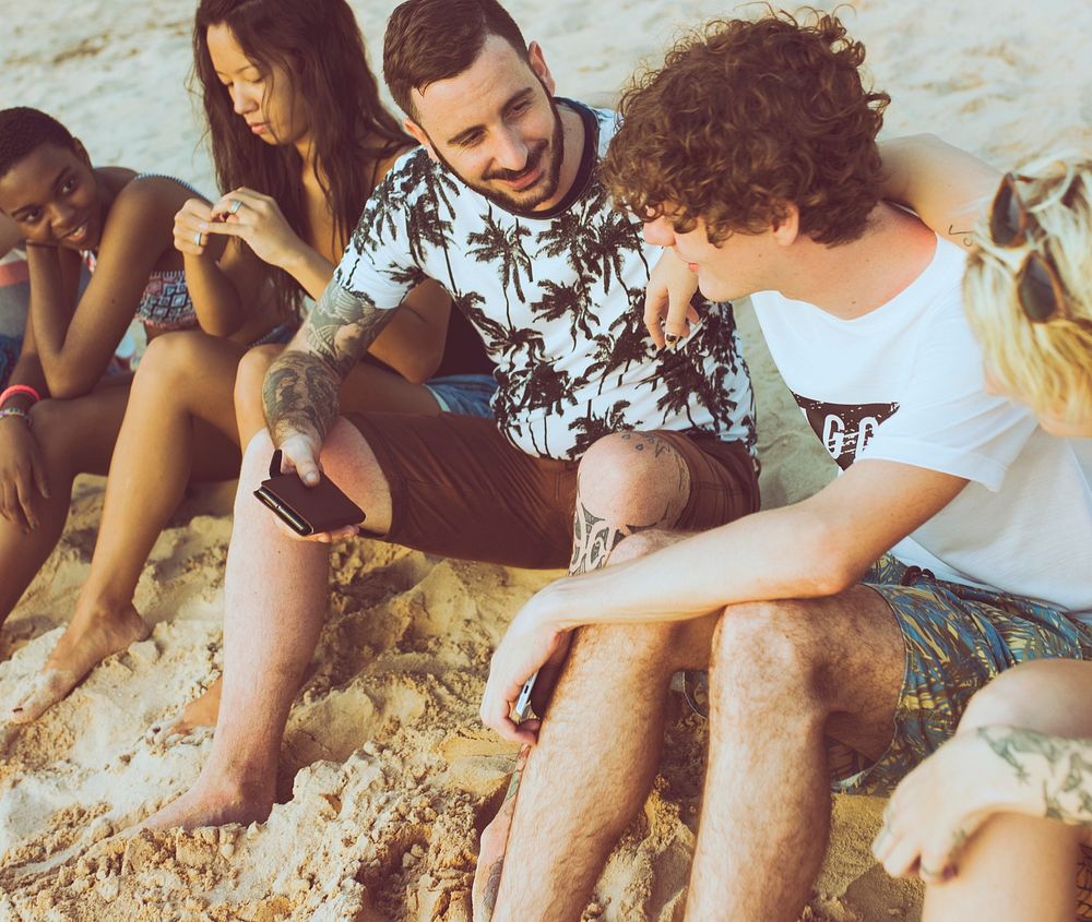 Group of diverse friends sitting at the beach together