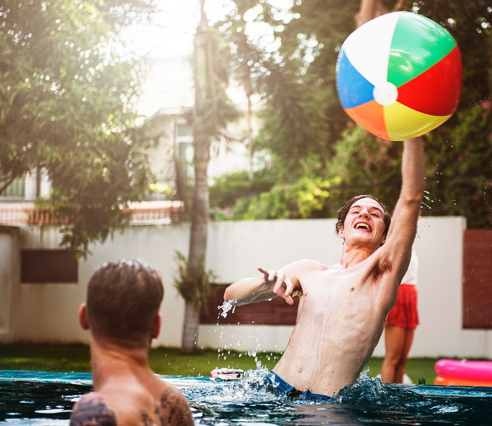 Diverse men playing beach inflatable ball in swimming pool