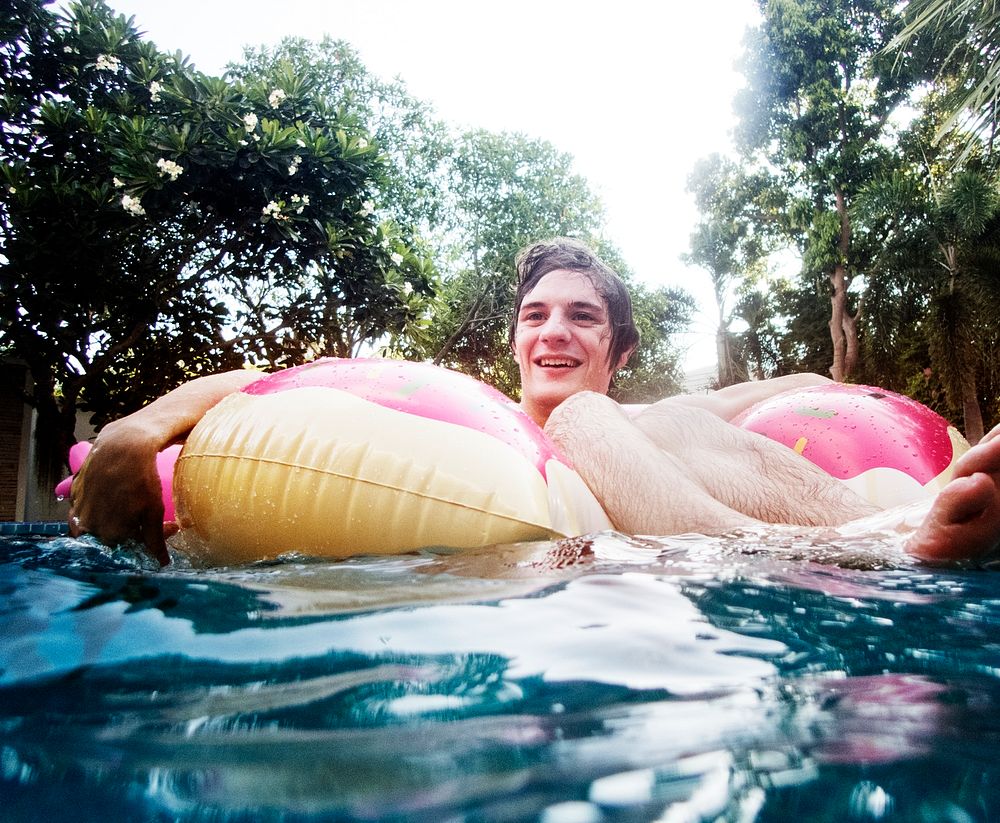 Caucasian man floating in the swimming pool by inflatable