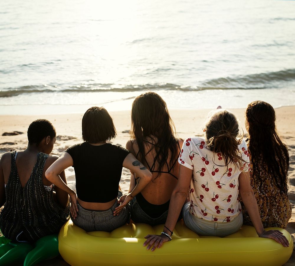 A diverse group of woman friends sitting at the beach together
