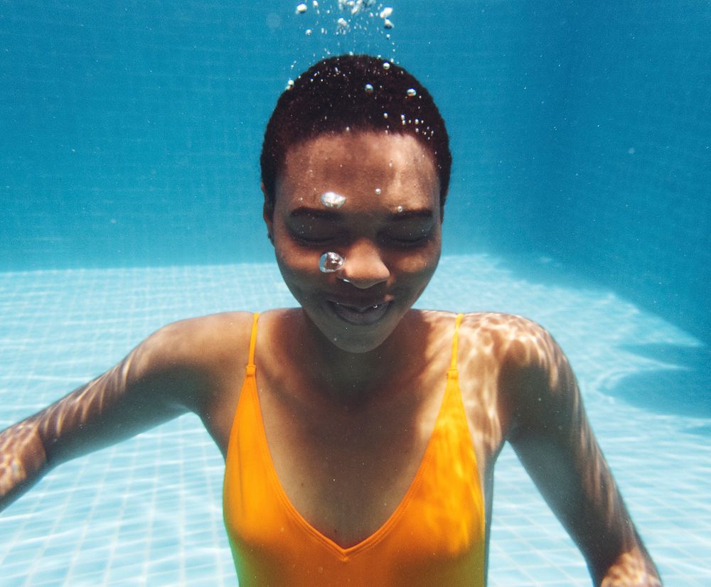 African descent woman smiling underwater in swimming pool