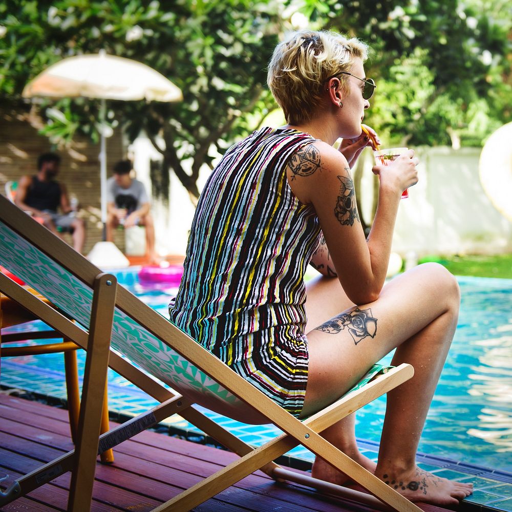 Caucasian girl drinks juice cocktail by a pool