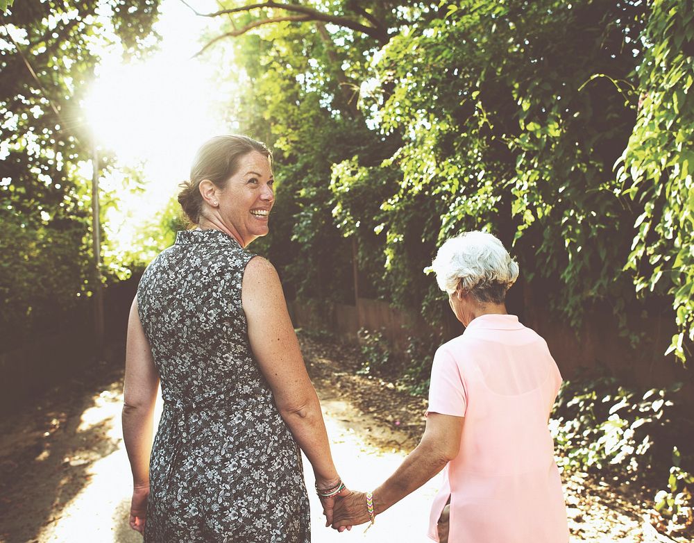 Two senior women holding hands walking outdoors