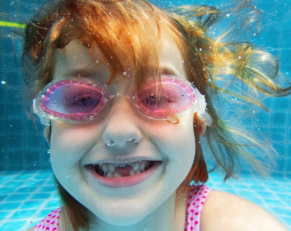 Girl with goggles diving in swimming pool