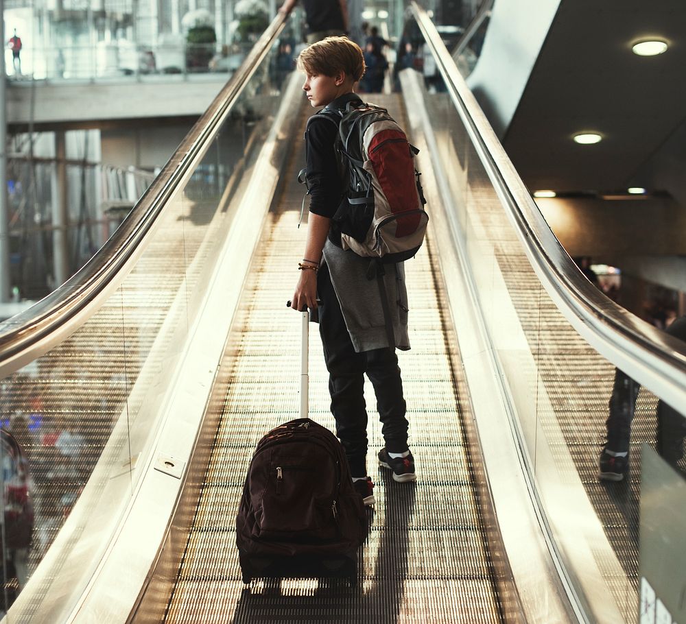 Young caucasian boy travel with luggage in the airport