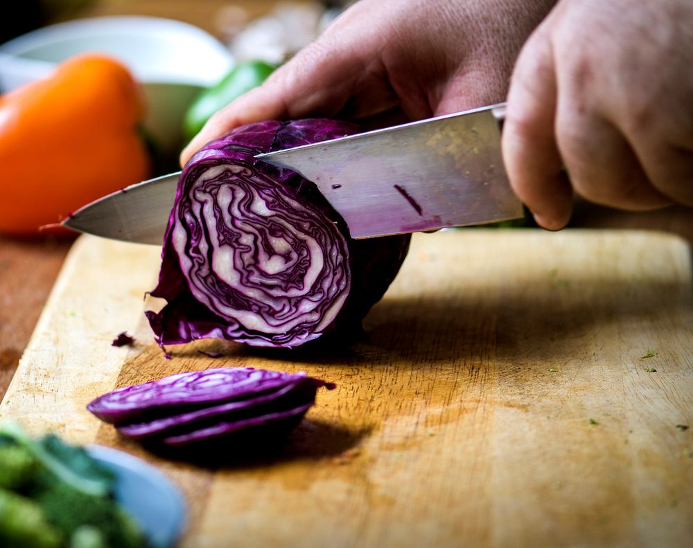 Hands using a knife chopping red cabbage