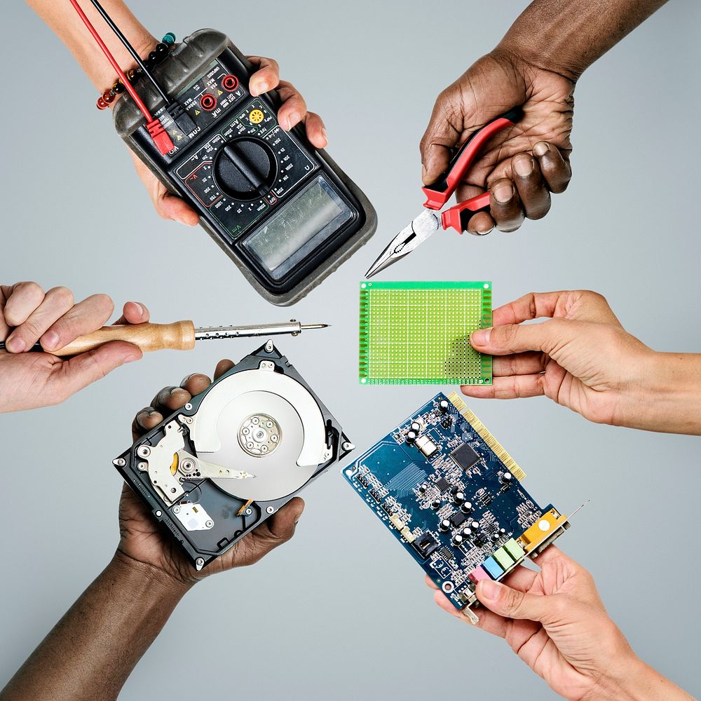 Group of hands holding computer electronics parts on gray background