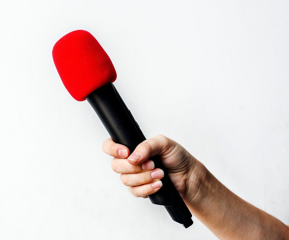 Hand holding microphone isolated on background