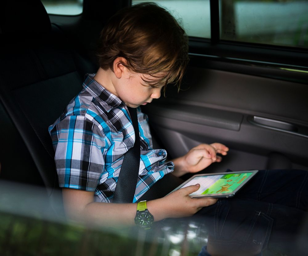 Young caucasian boy using digital tablet inside the car