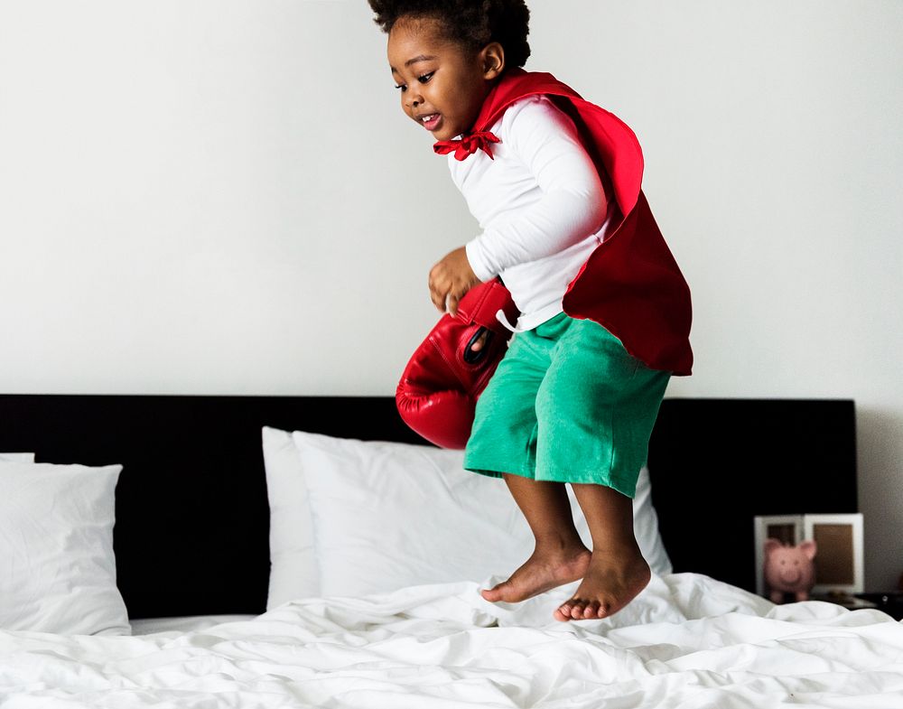 African descent kid jumping on the bed