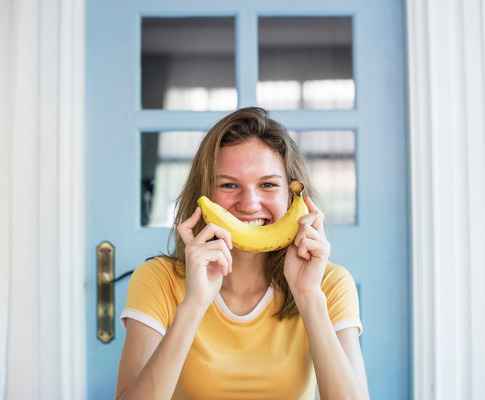 A Caucasian woman with banana and a smile on her face 