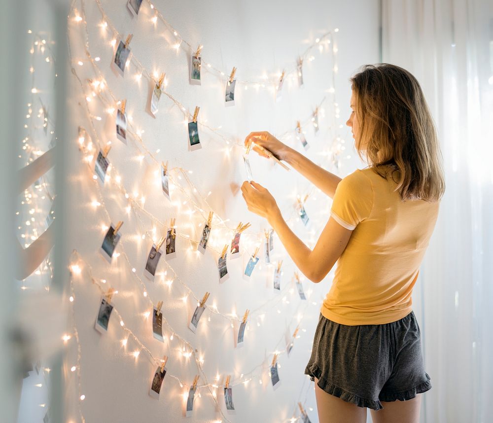 A woman looking at photos hanging on decoration lights