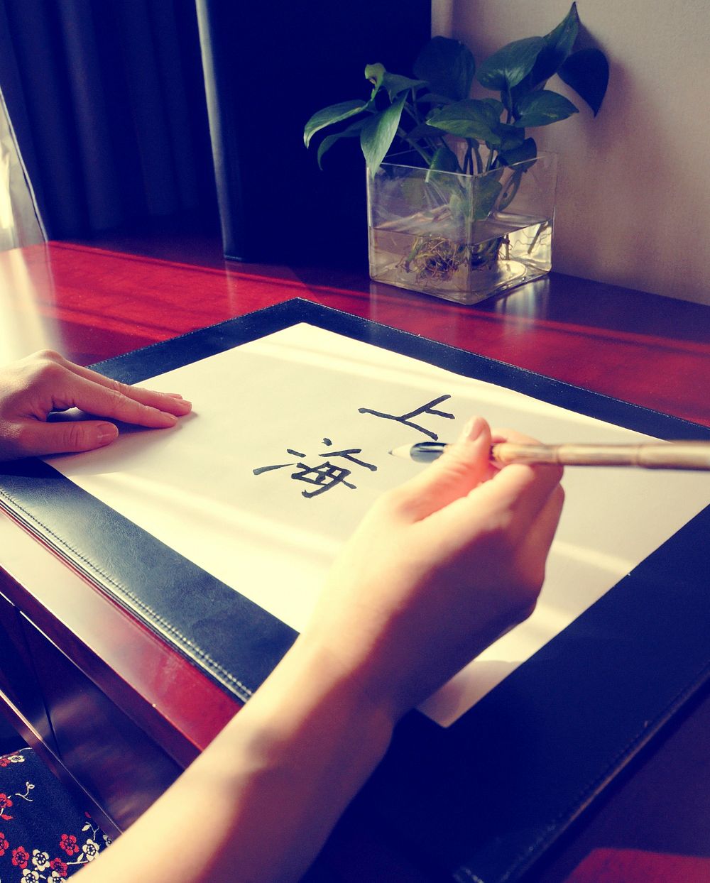 Close up of a lady writing "Shanghai" in Chinese.