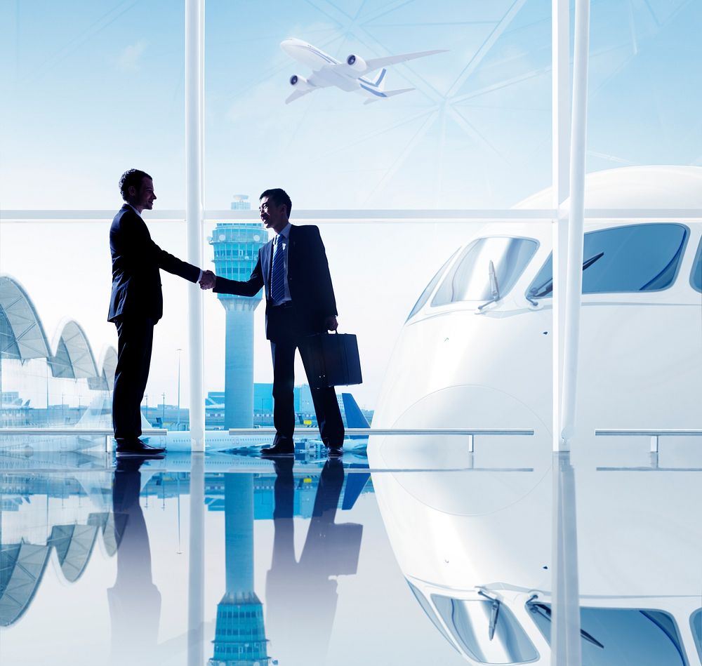 Two businessmen shaking hands in an airport.