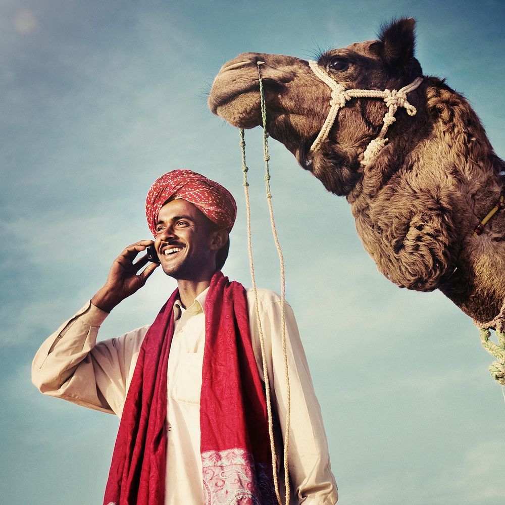 Indian man with camel talking on the phone