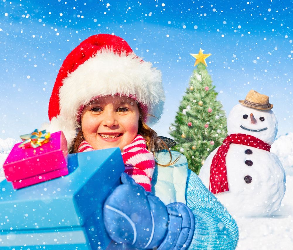 Happy little girl holding gifts and a snowman and christmas tree as a background