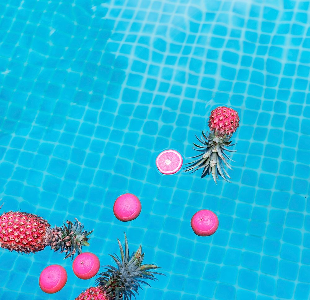 Aerial view of pineapple and oranges floating in a swimming pool