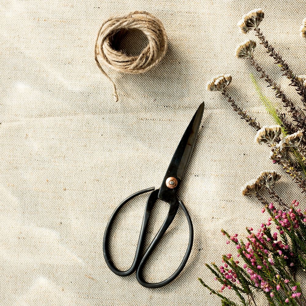 Aerial view of scissor and flowers on sackcloth background