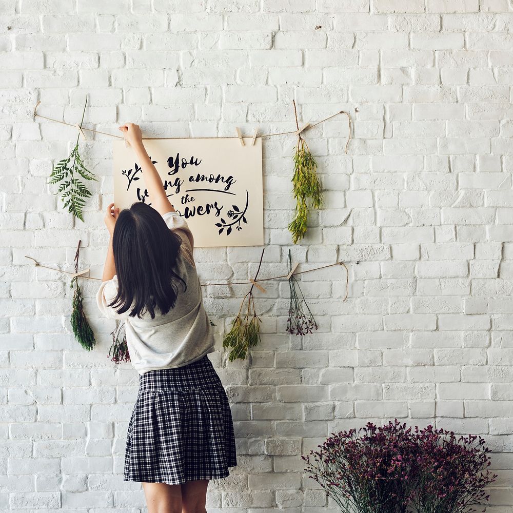 Rear view of woman hanging you belong among the flowers phrase paper with string