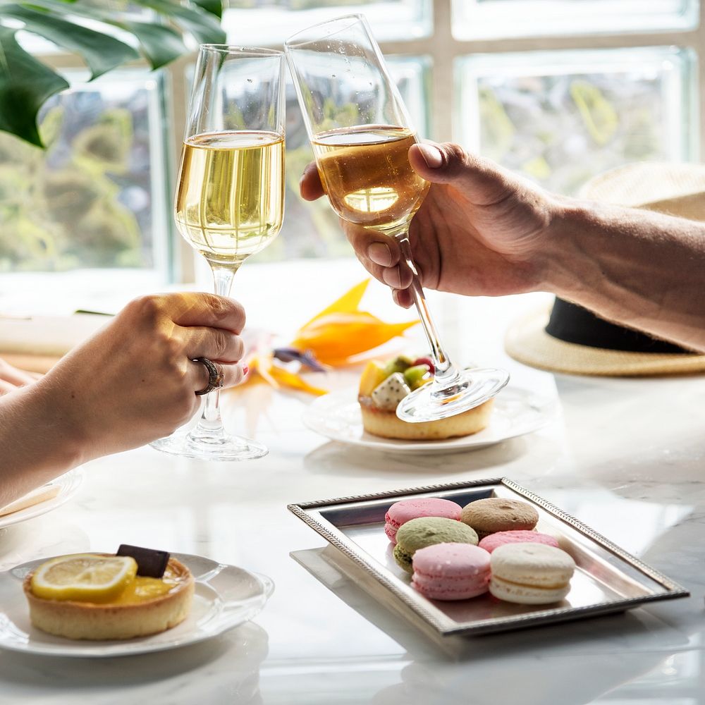 A couple in a date raising champagne glasses and having desserts at a restaurant