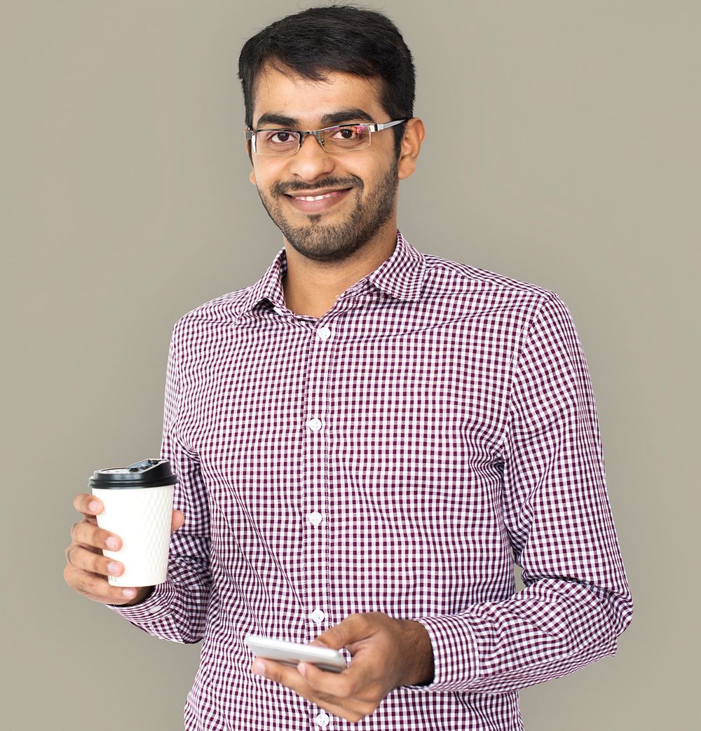 Studio portrait of a guy holding his mobile and coffee