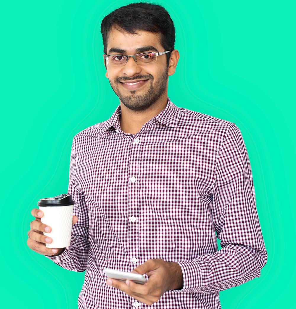 Studio portrait of a guy holding his mobile and coffee