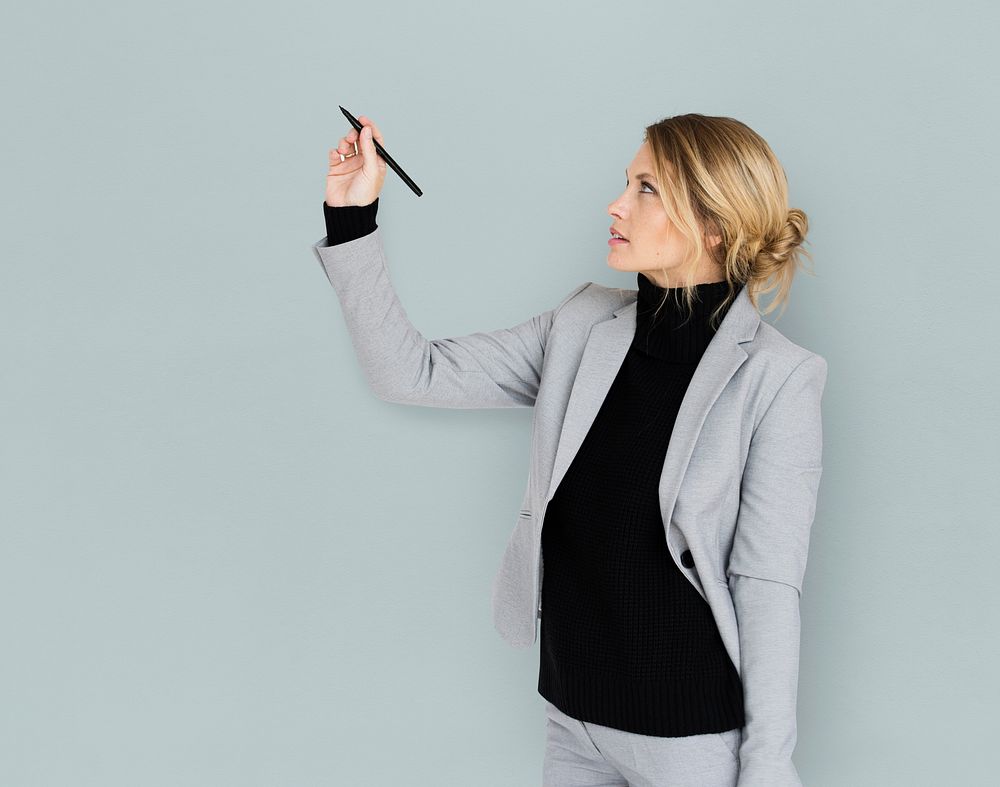 Studio portrait of a business woman writing on air with a pen