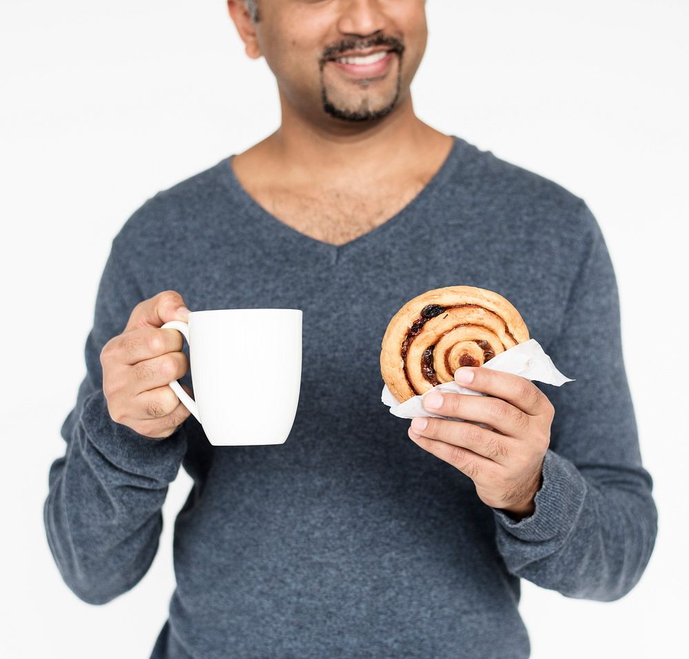 Adult man holding mug and bread roll