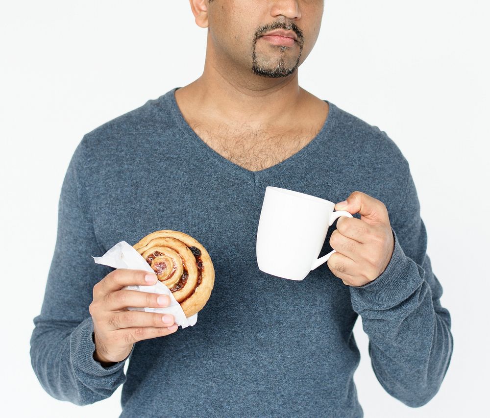 Adult man holding mug and bread roll