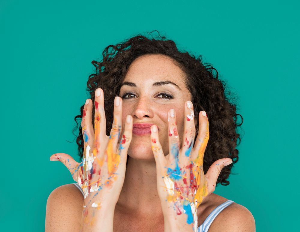 Studio portrait of a woman showing off her messy hands with paint