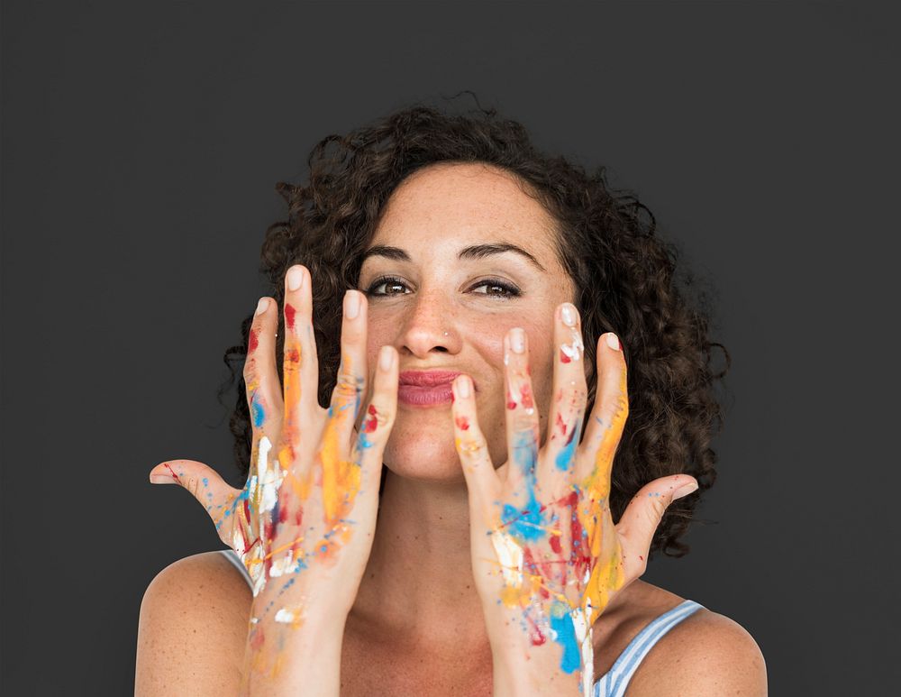 Studio portrait of a woman showing off her messy hands with paint