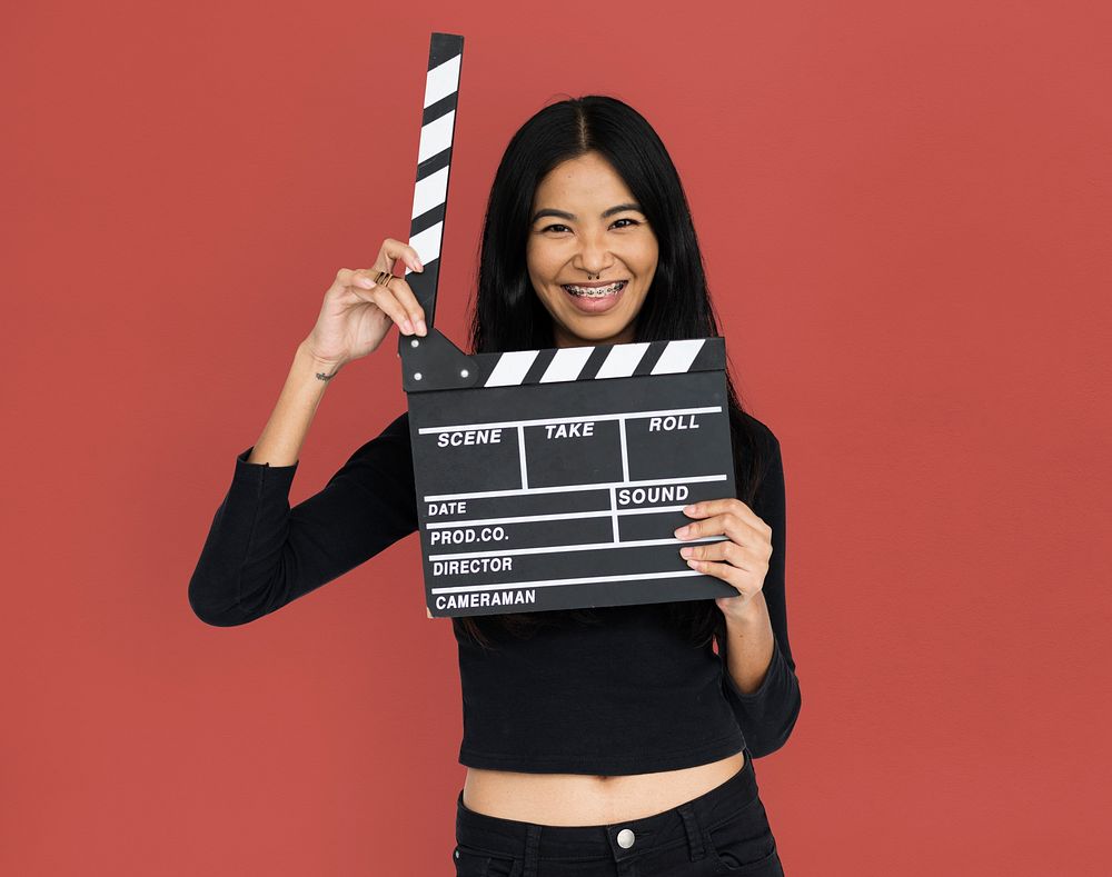 Young woman in croptop holding clapperboard