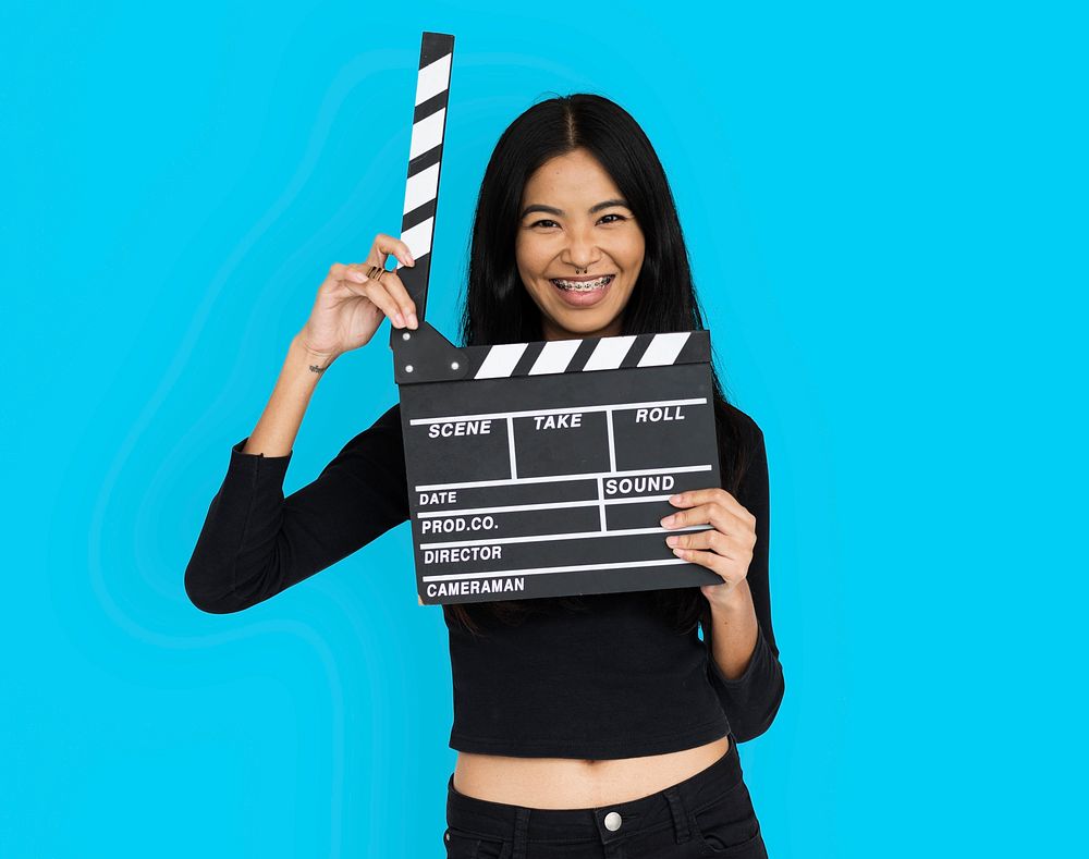 Young woman in croptop holding clapperboard