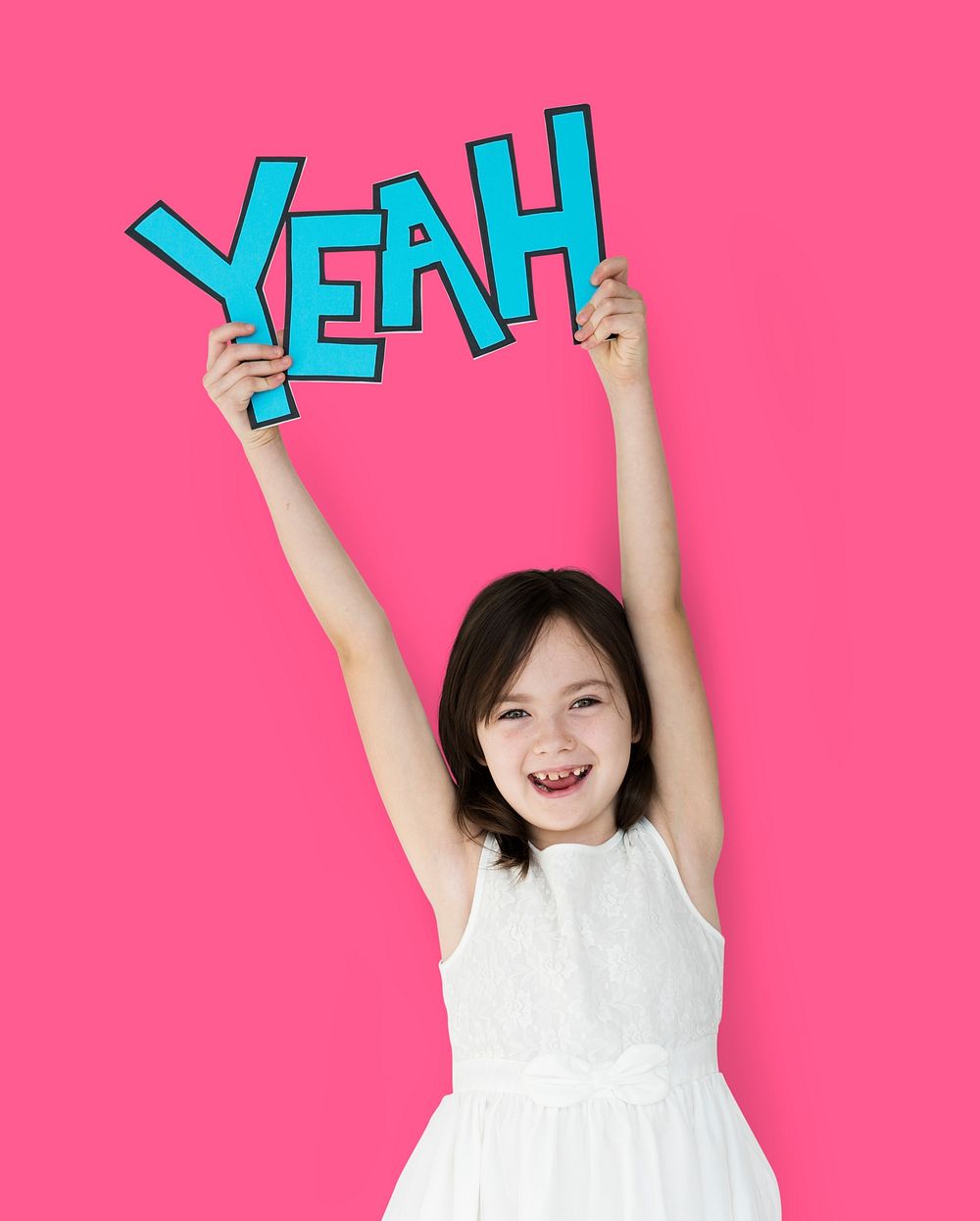 Cheerful girl holding out YEAH paper cutout